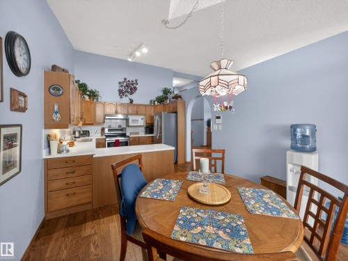 The kitchen features wood cabinetry, white countertops, and stainless steel appliances, including a microwave, oven, and refrigerator - 7 85 Gervais Road, St. Albert, AB - Indoor Photo Showing Dining Room