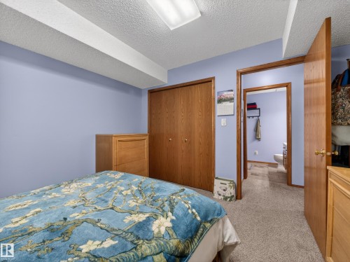 This bedroom features light blue walls, a carpeted floor, and a double-door wooden closet - 7 85 Gervais Road, St. Albert, AB - Indoor Photo Showing Bedroom
