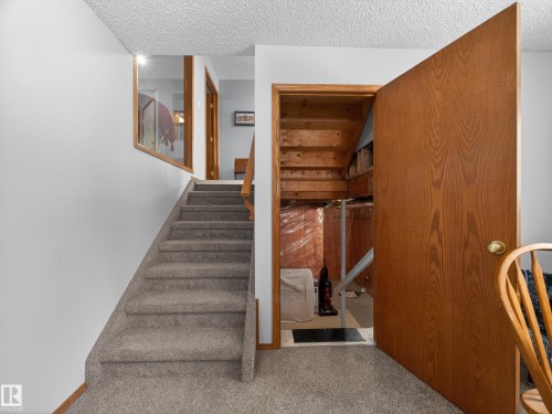 The property features carpeted stairs with a wooden handrail, leading to a landing with a window - 7 85 Gervais Road, St. Albert, AB - Indoor Photo Showing Other Room