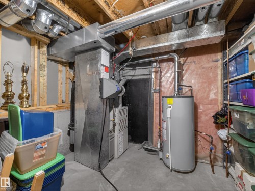 The property features a water heater and furnace, with exposed ductwork and ceiling joists - 7 85 Gervais Road, St. Albert, AB - Indoor Photo Showing Basement