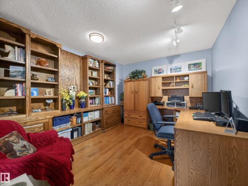 This room features extensive built-in wooden shelving, hardwood floors, and overhead lighting - 7 85 Gervais Road, St. Albert, AB - Indoor Photo Showing Office