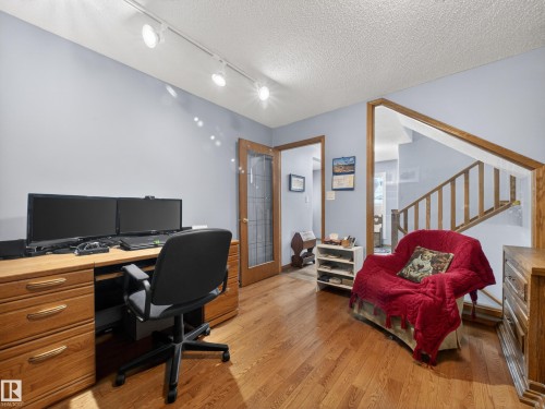 Versatile interior space featuring hardwood floors, track lighting, and a wooden staircase - 7 85 Gervais Road, St. Albert, AB - Indoor Photo Showing Office