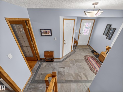 The property features an entryway with grey tile flooring, light blue walls, and a wood-framed door with glass inserts - 7 85 Gervais Road, St. Albert, AB - Indoor Photo Showing Other Room