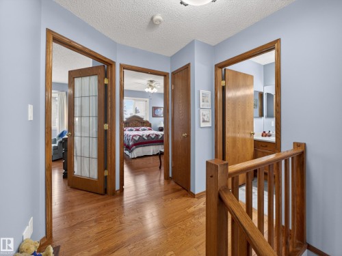 The property features hardwood flooring throughout this hallway, with light blue walls and natural wood trim and doors - 7 85 Gervais Road, St. Albert, AB - Indoor