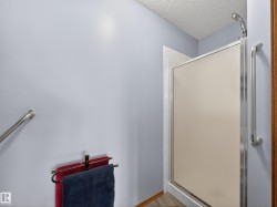 Bathroom featuring a shower with a frosted glass door, a mounted shower head, and an internal grab bar - 