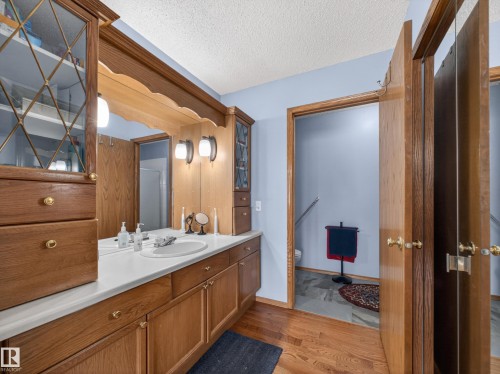 This bathroom features a large vanity with a white countertop, an integrated sink, and ample storage in wooden cabinetry with brass hardware - 7 85 Gervais Road, St. Albert, AB - Indoor Photo Showing Bathroom