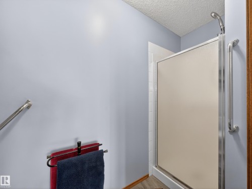 Bathroom featuring a shower with a frosted glass door, a mounted shower head, and an internal grab bar - 7 85 Gervais Road, St. Albert, AB - Indoor