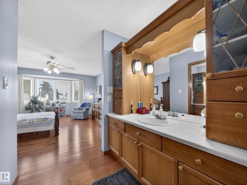 The property features a vanity with dual sinks, wooden cabinetry, and a large mirror - 7 85 Gervais Road, St. Albert, AB - Indoor