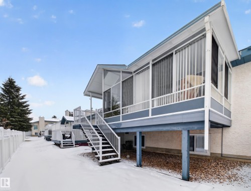 The property features a screened-in porch with an exterior staircase and a railing, providing outdoor space - 7 85 Gervais Road, St. Albert, AB - Outdoor