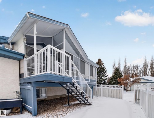 The property features an enclosed patio area with a white railing and exterior stairs, set against a light-colored exterior wall - 7 85 Gervais Road, St. Albert, AB - Outdoor