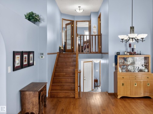 Spacious interior with hardwood flooring, a prominent wooden staircase, and light blue walls - 7 85 Gervais Road, St. Albert, AB - Indoor Photo Showing Other Room