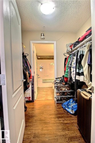 The property features a walk-in closet with warm-toned flooring and a flush-mount ceiling light fixture, leading to an additional room - 114 592 Hooke Road, Edmonton, AB - Indoor With Storage
