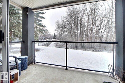 This property features a balcony with a concrete floor, dark grey support pillars, and a glass railing with a black top rail - 114 592 Hooke Road, Edmonton, AB - Outdoor
