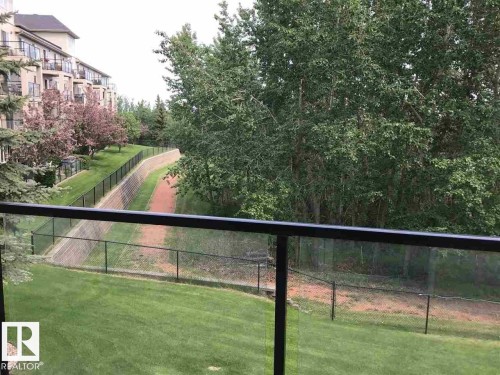 The property offers views of mature trees, a well-maintained lawn, and a paved pathway - 114 592 Hooke Road, Edmonton, AB - Outdoor