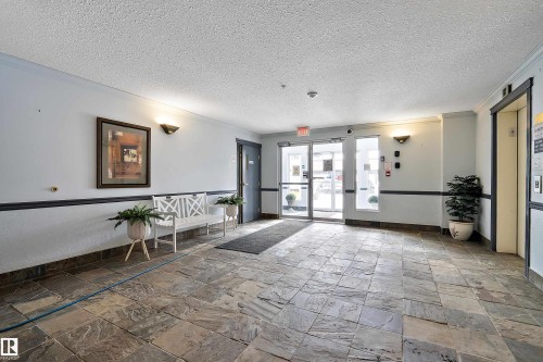 Lobby area featuring natural stone tile flooring, a seating bench, and an elevator - 114 592 Hooke Road, Edmonton, AB - Indoor Photo Showing Other Room