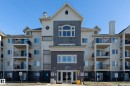 The property features a multi-story building with balconies, a prominent main entrance, and a light-colored exterior with darker accents - 114 592 Hooke Road, Edmonton, AB  - Outdoor With Facade 