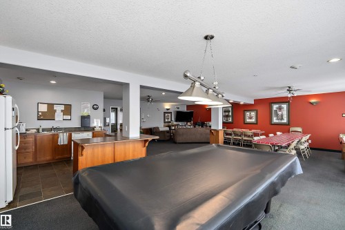 Recreational area featuring a pool table, kitchen area with appliances, and a dining space with tables and chairs - 114 592 Hooke Road, Edmonton, AB - Indoor