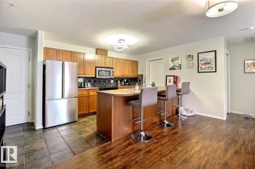 The kitchen features hardwood cabinetry, stainless steel appliances, and a central island with a wood countertop - 114 592 Hooke Road, Edmonton, AB - Indoor Photo Showing Kitchen