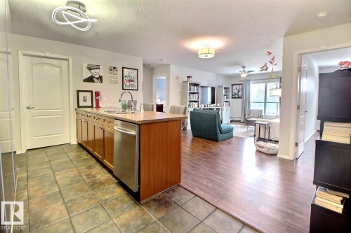 Open concept living area with diverse flooring, featuring tile in the kitchen area and wood flooring in the living room - 114 592 Hooke Road, Edmonton, AB - Indoor Photo Showing Kitchen With Double Sink
