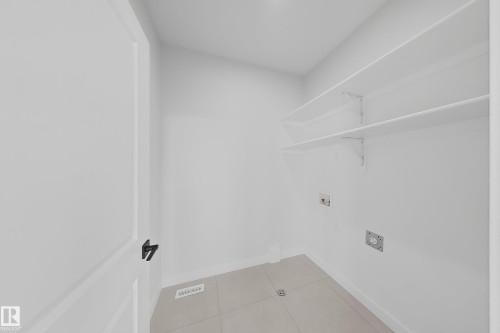 Utility room with white walls, built-in shelving, and light-colored floor tiles - 6449 28 Avenue, Edmonton, AB - Indoor