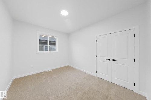 Room featuring light-colored carpet flooring, a window, white walls, and a closet with bifold doors - 6449 28 Avenue, Edmonton, AB - Indoor Photo Showing Other Room