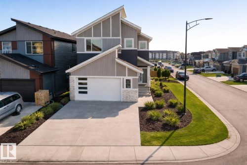 The property features modern architectural design with a white garage door, a concrete driveway, and front landscaping with shrubs - 6449 28 Avenue, Edmonton, AB - Outdoor With Facade