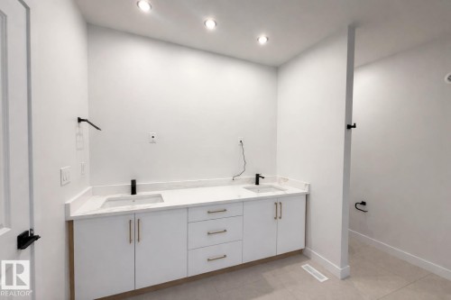Bathroom featuring a vanity with two sinks, white cabinetry, and gold-toned hardware - 6449 28 Avenue, Edmonton, AB - Indoor Photo Showing Other Room