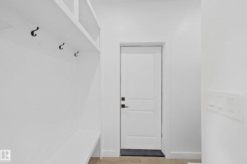 The property features a built-in mudroom bench with hooks, a white panel door, and light-colored flooring - 6449 28 Avenue, Edmonton, AB - Indoor Photo Showing Other Room