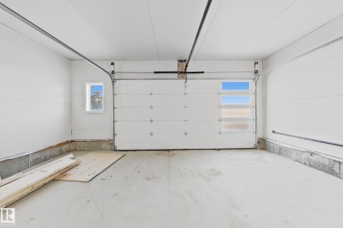 The garage features a white sectional door with four rectangular windows and a smaller window on the side wall - 6449 28 Avenue, Edmonton, AB - Indoor Photo Showing Garage