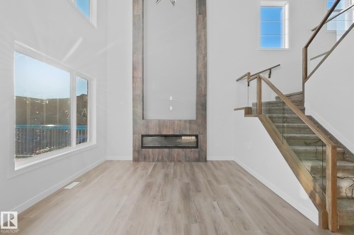 The property features an open-concept living space with light-colored flooring, a modern fireplace with a tiled surround, and large windows that provide natural light - 6449 28 Avenue, Edmonton, AB - Indoor Photo Showing Other Room