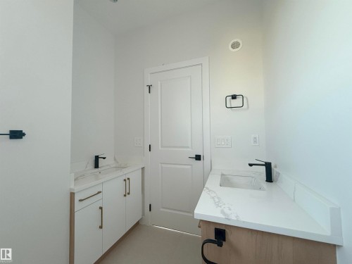 Bathroom featuring two white vanities with white countertops and sinks, and matte black faucets - 6449 28 Avenue, Edmonton, AB - Indoor Photo Showing Bathroom