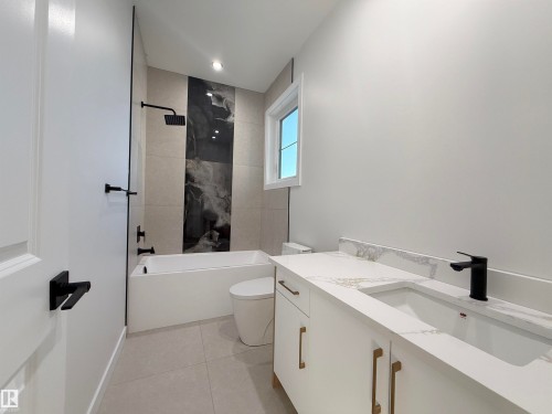 The bathroom features a modern vanity with a white countertop and rectangular sink, complemented by a black faucet - 6449 28 Avenue, Edmonton, AB - Indoor Photo Showing Bathroom