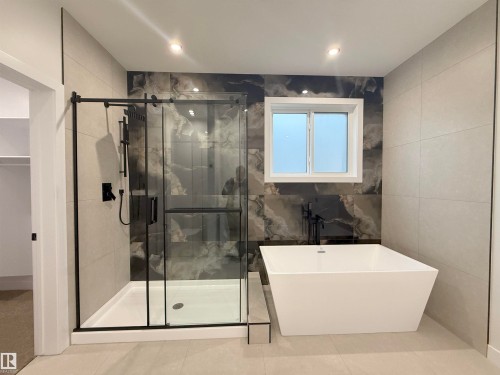 Bathroom featuring a freestanding white bathtub, a walk-in shower with black-framed glass doors, and recessed lighting - 6449 28 Avenue, Edmonton, AB - Indoor Photo Showing Bathroom