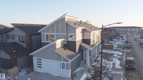 The property features a modern exterior with a mix of light and dark siding, a white garage door, and a multi-level roofline - 6449 28 Avenue, Edmonton, AB - Outdoor