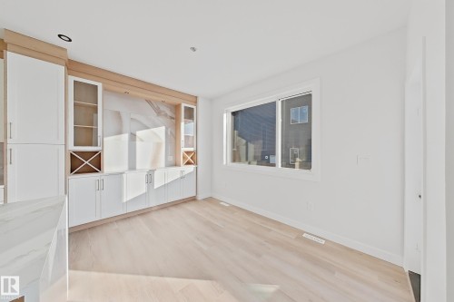 This room features light-toned hardwood flooring and a large window, providing natural light - 6449 28 Avenue, Edmonton, AB - Indoor Photo Showing Other Room