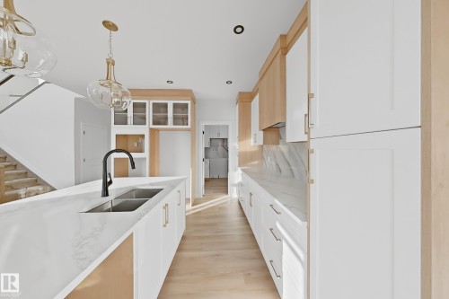 The kitchen features a large island with a double sink and a matte black faucet, surrounded by light wood flooring - 6449 28 Avenue, Edmonton, AB - Indoor Photo Showing Kitchen With Double Sink With Upgraded Kitchen