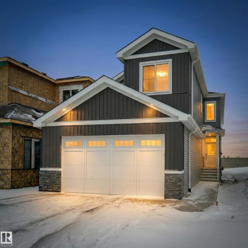 The property features a dark grey exterior with white trim, a double garage with frosted glass panels, and stone detailing around the base - 803 30 Avenue, Edmonton, AB - Outdoor