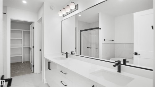 The bathroom features a double vanity with white countertops, integrated sinks, and matte black faucets - 803 30 Avenue, Edmonton, AB - Indoor Photo Showing Bathroom