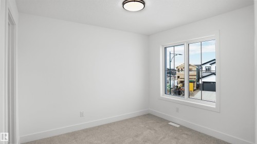 The property features a room with light-colored carpet, white walls, and a window providing natural light - 803 30 Avenue, Edmonton, AB - Indoor Photo Showing Other Room