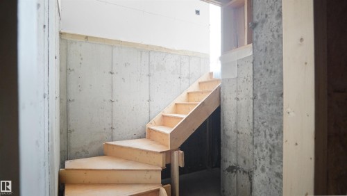 The property features an unfinished wooden staircase and concrete walls, with exposed wooden framing visible - 803 30 Avenue, Edmonton, AB - Indoor Photo Showing Other Room