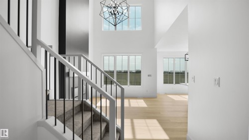 The property features high ceilings with large windows, light hardwood floors, and a geometric chandelier - 803 30 Avenue, Edmonton, AB - Indoor Photo Showing Other Room