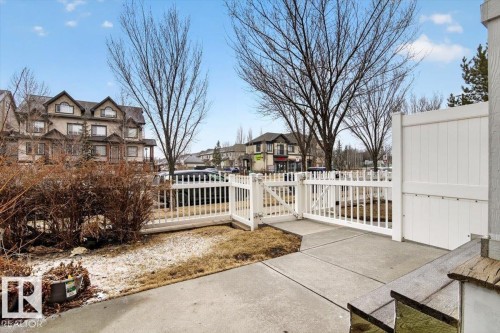The property features a white picket fence with a gate, a concrete patio, and mature trees - 1637 Towne Centre Boulevard, Edmonton, AB - Outdoor