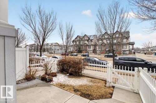 The property features a white picket fence enclosing a small garden area with shrubs and a concrete path - 1637 Towne Centre Boulevard, Edmonton, AB - Outdoor