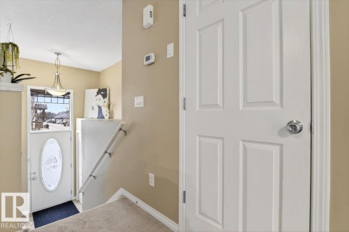 Inviting entryway featuring a white door with an oval glass insert, a light fixture, and carpeted stairs - 1637 Towne Centre Boulevard, Edmonton, AB - Indoor Photo Showing Other Room