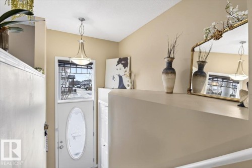 Welcoming entryway with a white door featuring an oval glass insert, a transom window, and a stylish ceiling light fixture - 1637 Towne Centre Boulevard, Edmonton, AB - Indoor Photo Showing Other Room