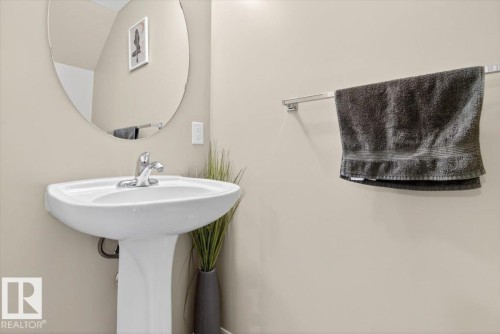 Bathroom featuring a white pedestal sink with a chrome faucet and an oval mirror - 1637 Towne Centre Boulevard, Edmonton, AB - Indoor Photo Showing Bathroom