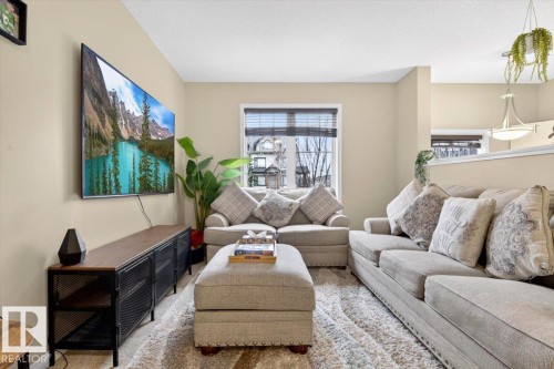 The living area features neutral-toned walls, a window with blinds, and a light-colored area rug - 1637 Towne Centre Boulevard, Edmonton, AB - Indoor Photo Showing Living Room