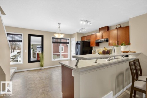 The kitchen features wood cabinetry, black appliances, and a breakfast bar with a sink - 1637 Towne Centre Boulevard, Edmonton, AB - Indoor
