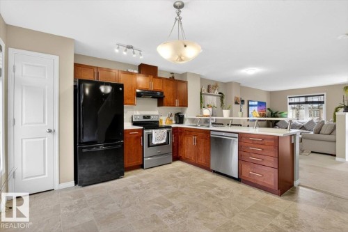The kitchen features wood cabinetry, stainless steel appliances, and a tiled floor - 1637 Towne Centre Boulevard, Edmonton, AB - Indoor Photo Showing Kitchen