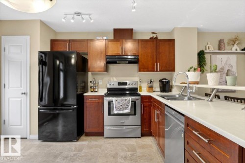 The kitchen features wood cabinetry, light countertops, and stainless steel appliances including a range and dishwasher - 1637 Towne Centre Boulevard, Edmonton, AB - Indoor Photo Showing Kitchen With Double Sink
